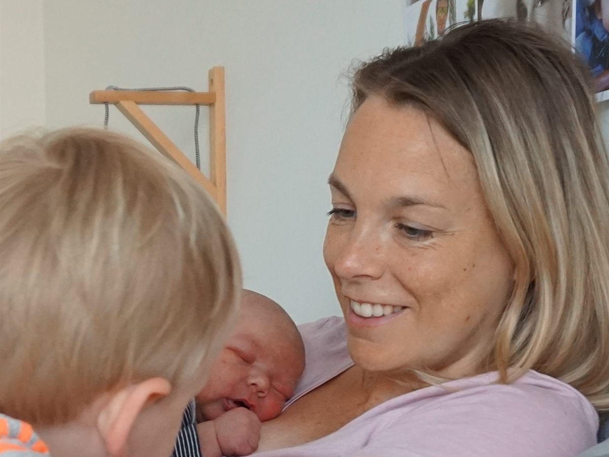 Yanieke met haar pasgeboren baby op haar borst, terwijl haar oudste kindje toekijkt.